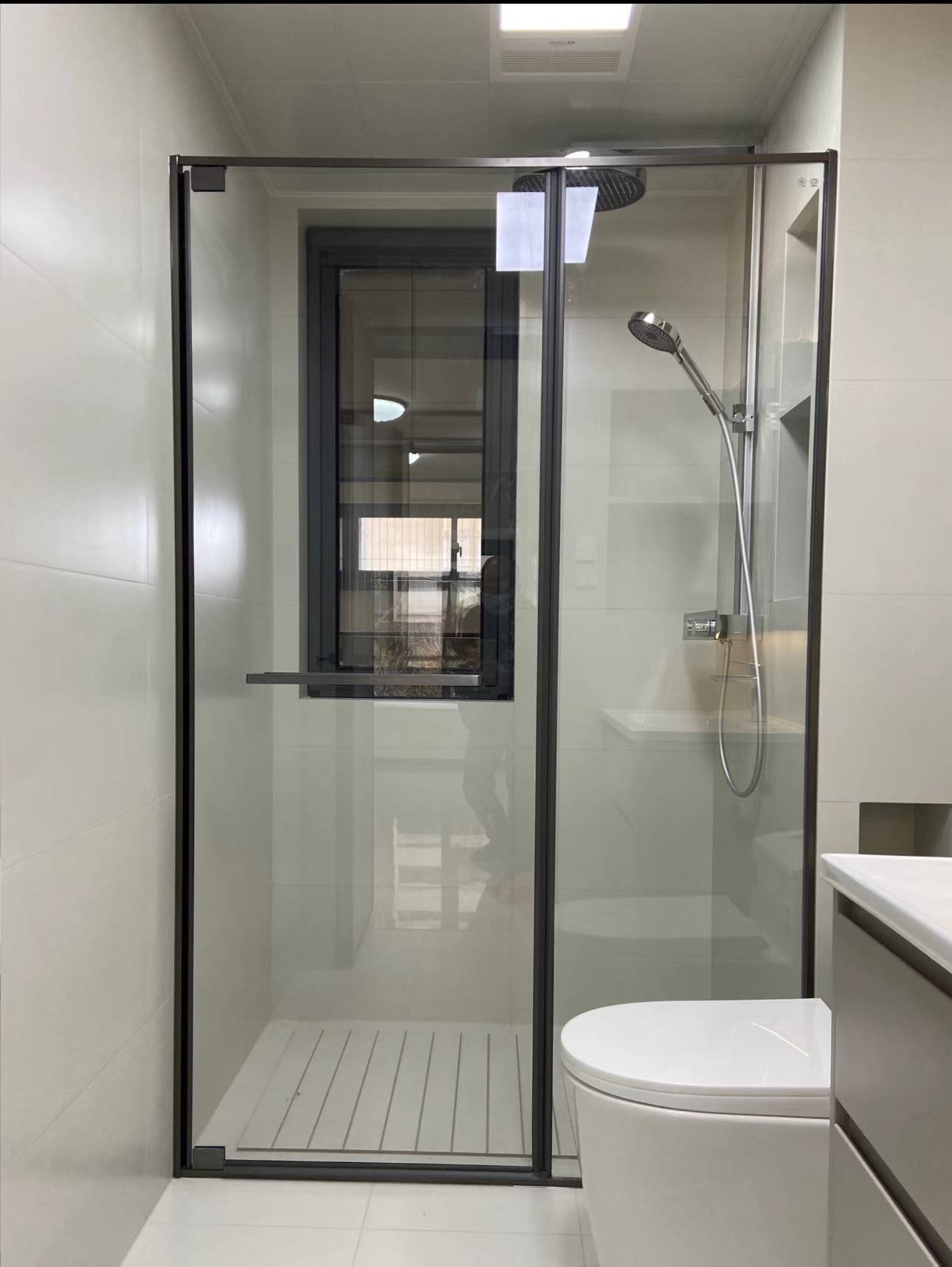 Black framed shower door system with a slim stainless steel top track