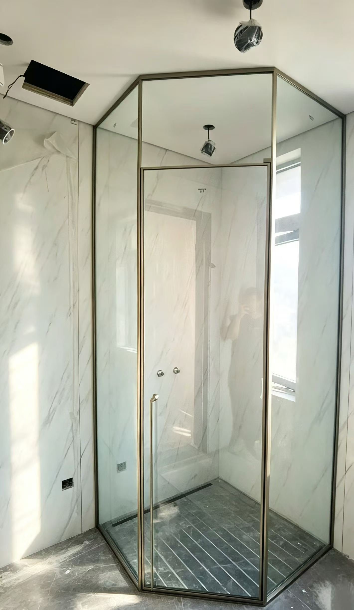 Champagne stainless steel trim framing a floor-to-ceiling glass shower enclosure