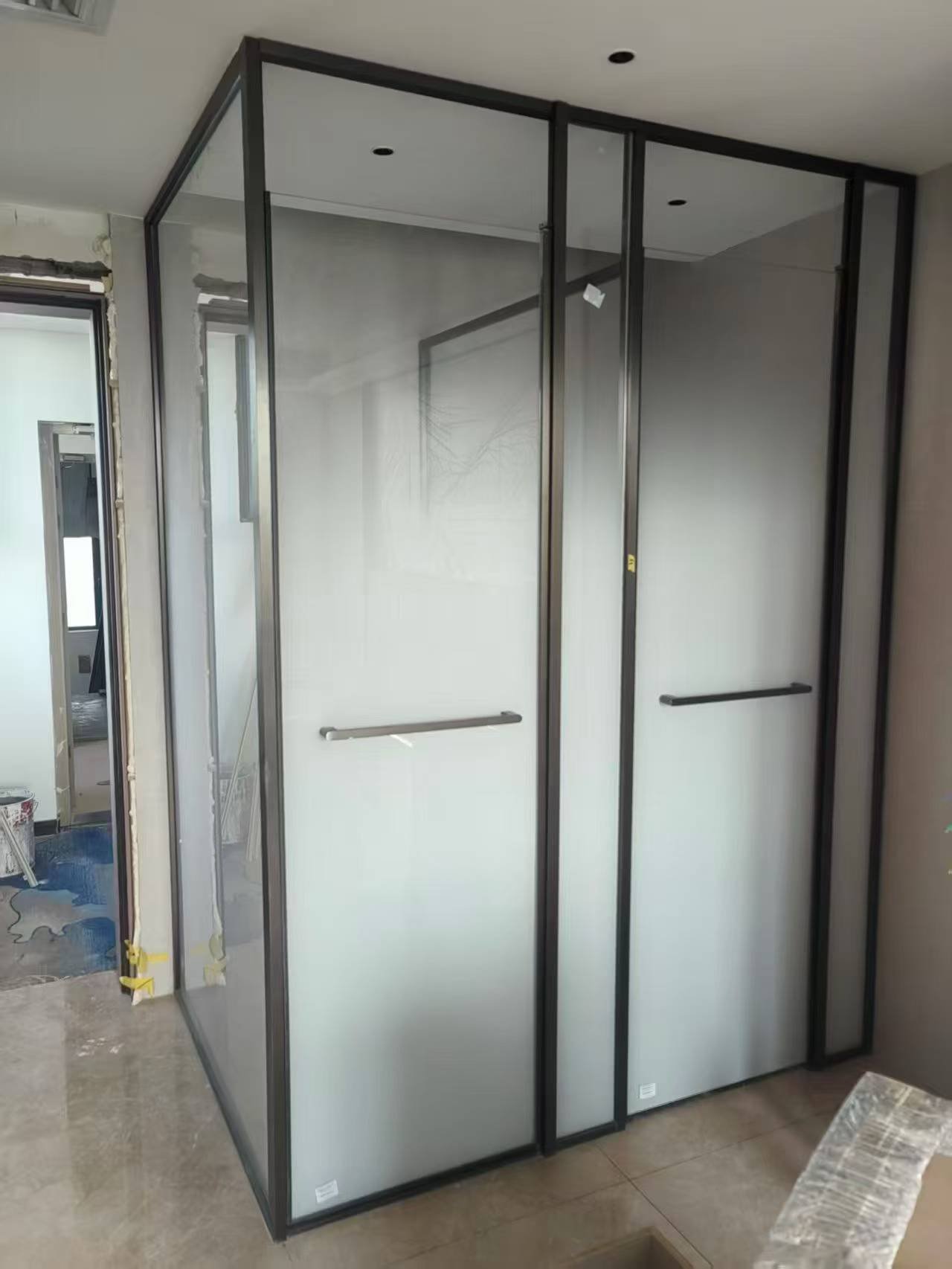 Floor-to-ceiling frosted glass partition system with slim black metal frames